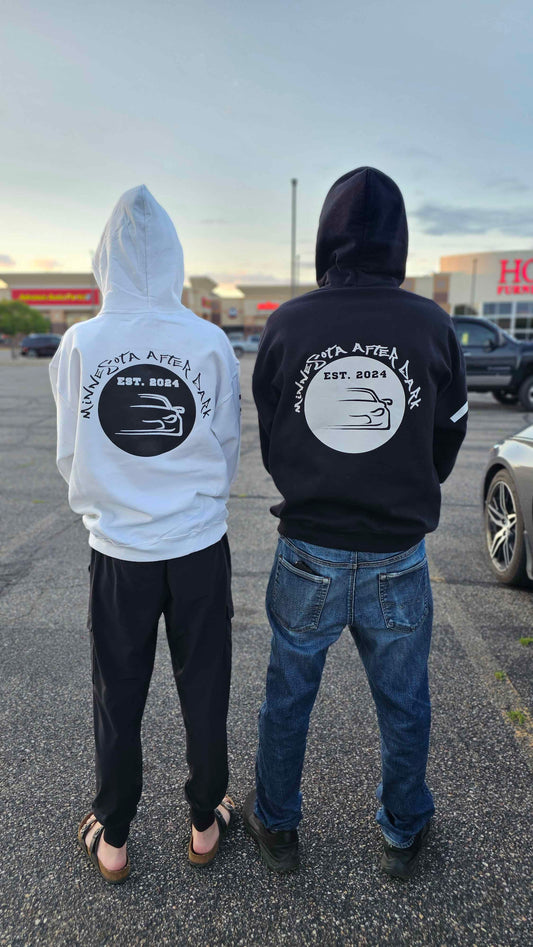 Two people wearing hoodies with logos on the back in a parking lot.